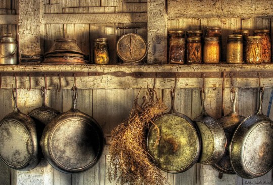 Spices and hanging frying pans in rustic kitchen